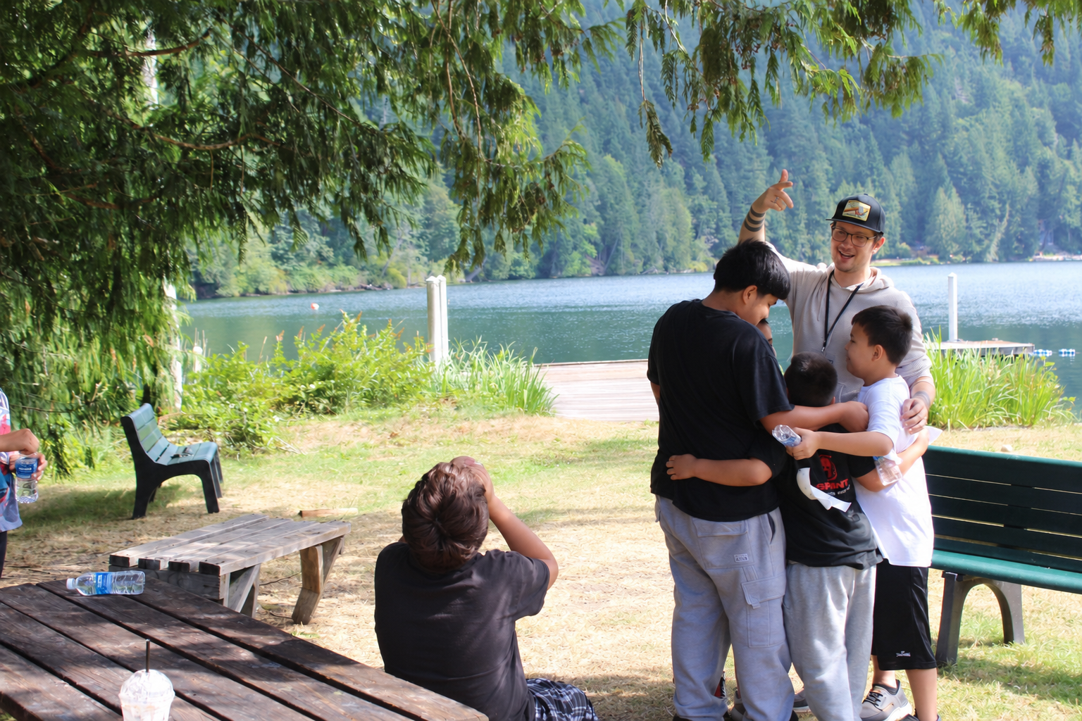 Campers gathered with a caring adult beside the lake