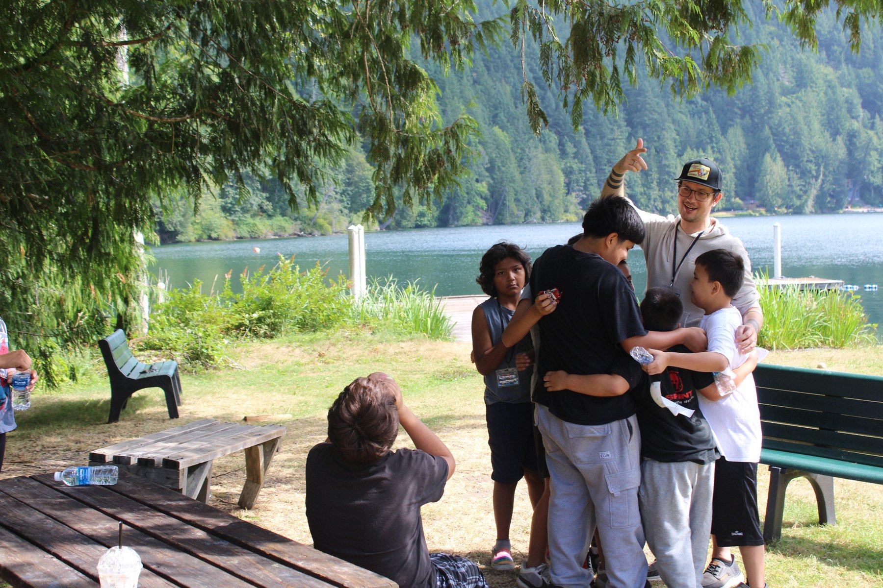 Campers gathered with a caring adult beside the lake