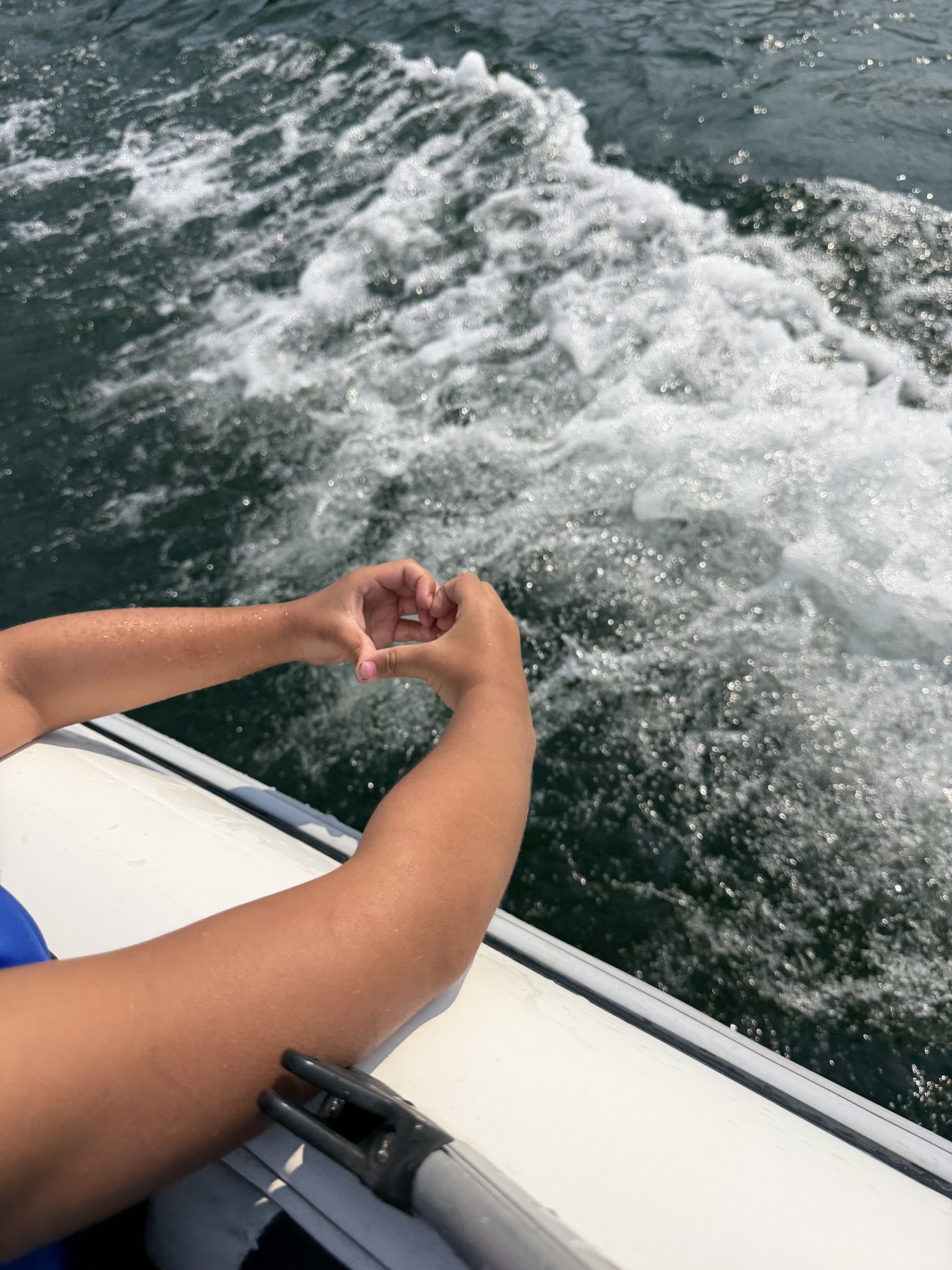 Hands forming a heart above the water