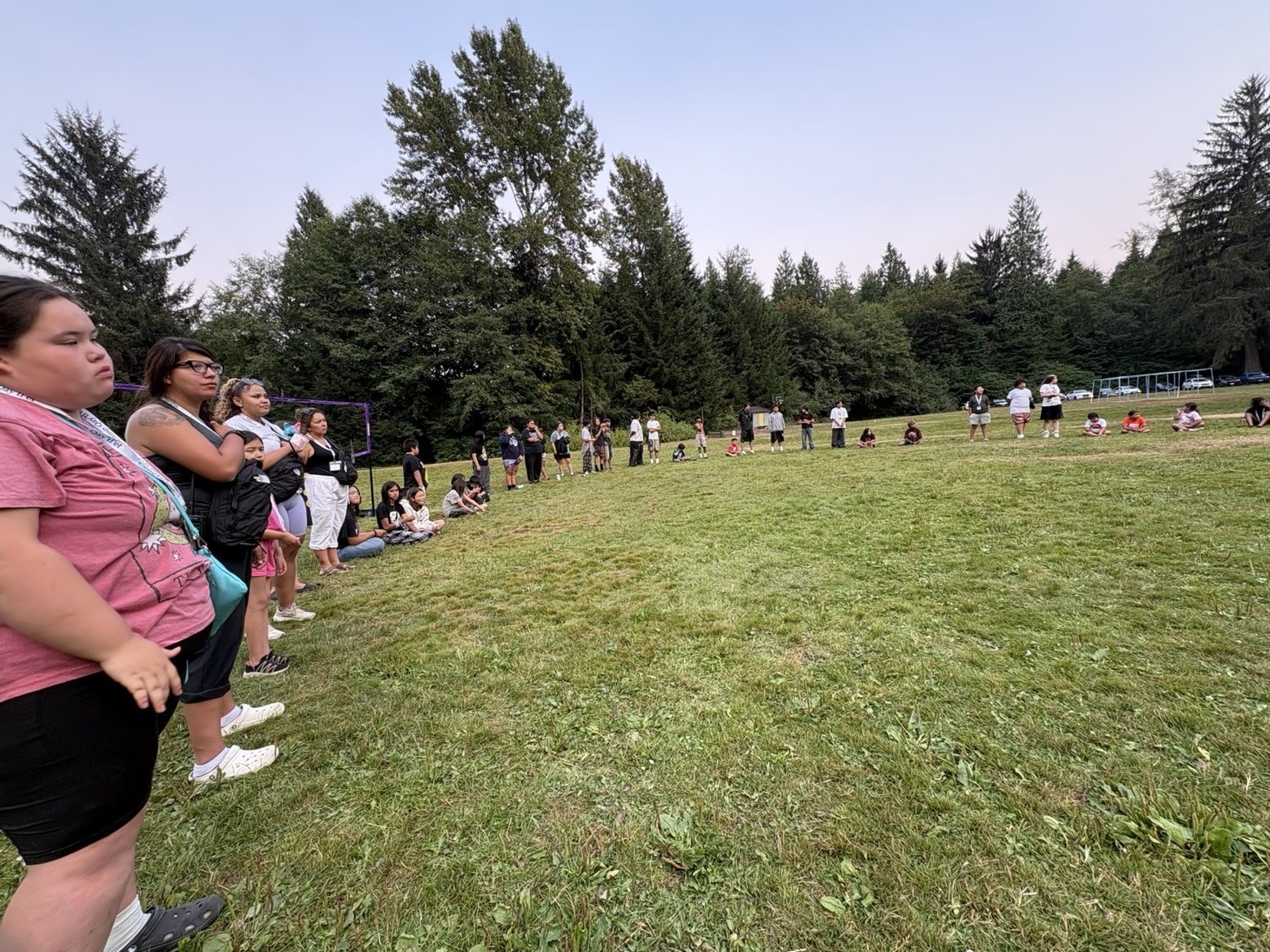 Community members gathered in a grassy field at camp
