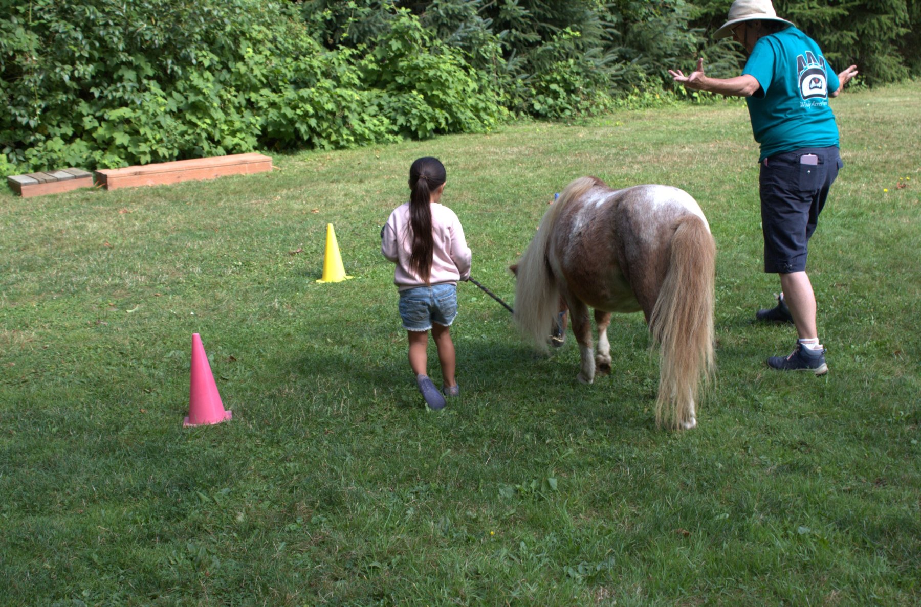 A camper and adult walking beside a miniature horse